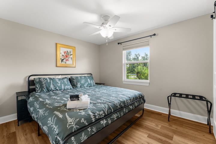 Letto matrimoniale grande con portavaligie e tende oscuranti per la stanza.  La biancheria da letto include un materasso in memory foam e lenzuola bianche in 100% cotone.  I tavolini sono dotati di caricabatterie USB.