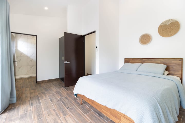 Een ander uitzicht op de primaire slaapkamer met een kingsize bed, een kast en een deur naar de eigen badkamer.