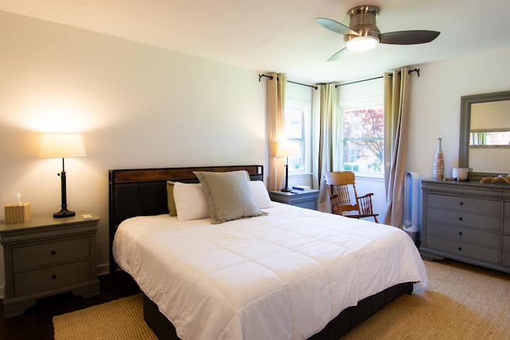Chambre lumineuse et chaleureuse avec lumière naturelle, ventilateur de plafond et décor neutre élégant
