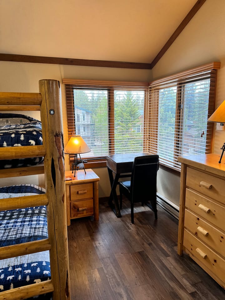 Svetlá a vzdušná tretia spálňa na prízemí v rohu so samostatnou posteľou nad ďalšou samostatnou posteľou.