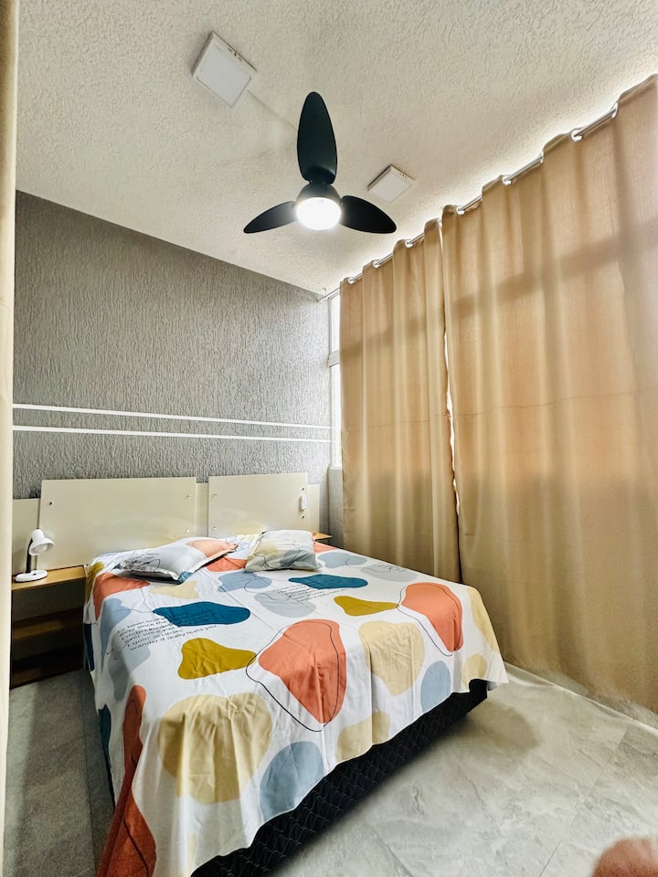 Chambre avec un ventilateur de plafond au-dessus du lit.