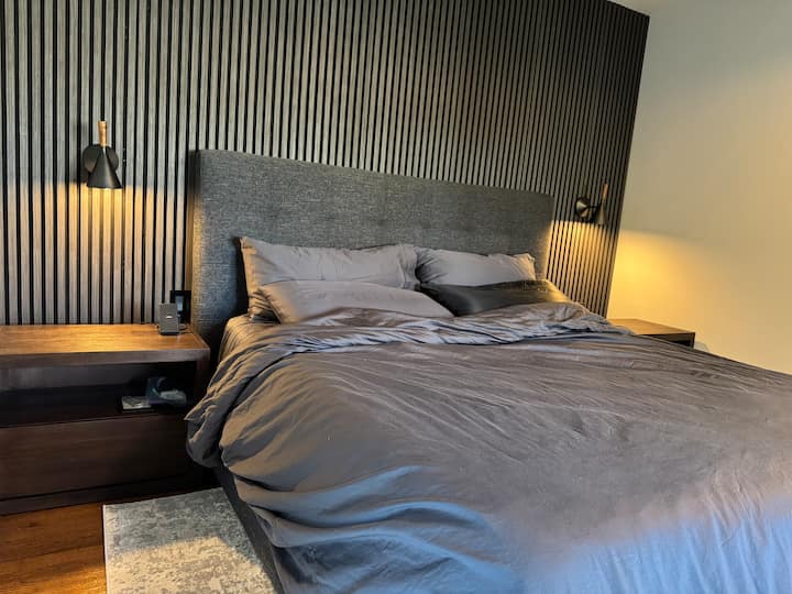 Primárna spálňa s luxusnou posteľnou bielizňou a fialovou manželskou posteľou veľkosti King. 