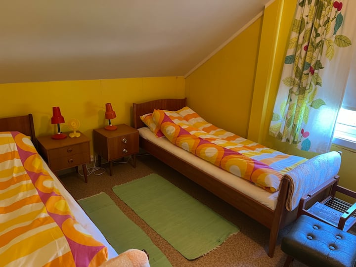 Стаята в стил 60 -70 - те! Свежи цветове и мебели от тиково дърво. Ето 2 единични легла, които могат да бъдат преместени заедно в двойно легло, ако желаете. Скрин с огледало, нощно шкафче и стол в стаята. В гардероба има допълнително спално бельо, завивки, възглавници и одеяла