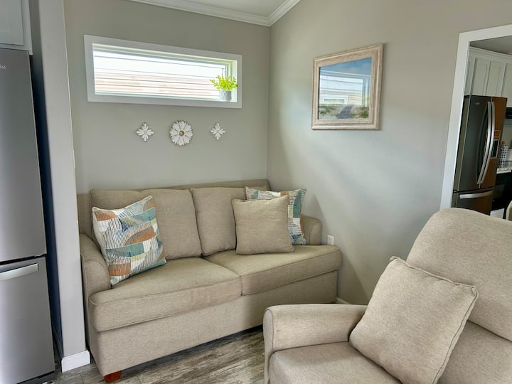 Komfortables und gemütliches Wohnzimmer mit Couch und Liegestuhl. Zwei Einzel-Luftmatratzen und Ersatzbettwäsche für zusätzliche Schlafgelegenheiten werden bereitgestellt. 