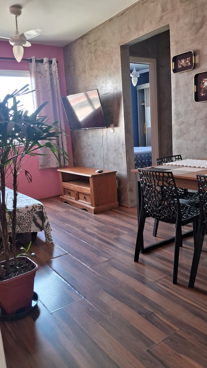 غرفة معيشة مع تلفزيون ذكي وسرير أريكة ومروحة سقف. 