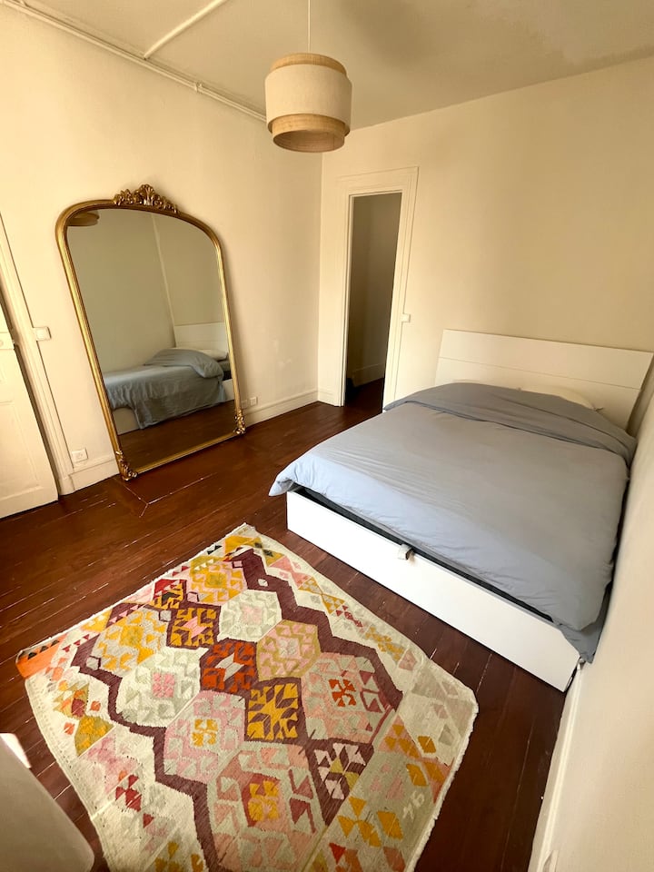 Habitación cómoda y luminosa con cama de matrimonio con espacio de almacenamiento, suelo de parqué de madera y decoración cuidada. Gran espejo de pie, alfombra de colores cálidos y ambiente acogedor. Espacio tranquilo, agradable y funcional, ideal para estancia o alquiler