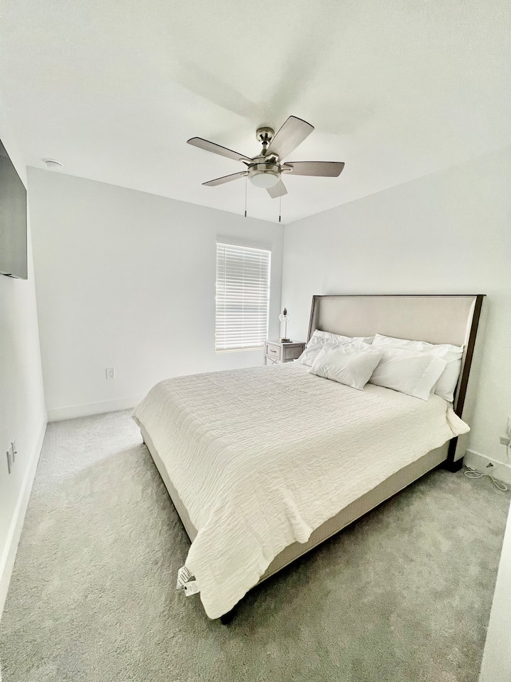 Acogedor dormitorio con cama tamaño queen, televisor grande de pantalla plana y armario completo para almacenamiento. 