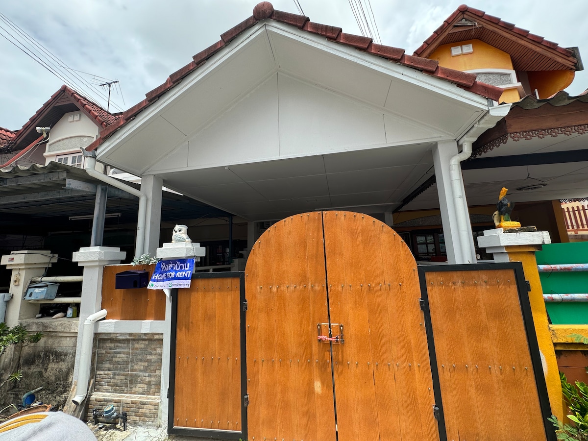 A spacious entrance is framed by a large, wooden barn-style door, showcasing a warm, natural finish. The roofline features a gentle slope, and surrounding structures blend harmoniously, hinting at a welcoming atmosphere. The area is well-lit, contributing to a friendly exterior.