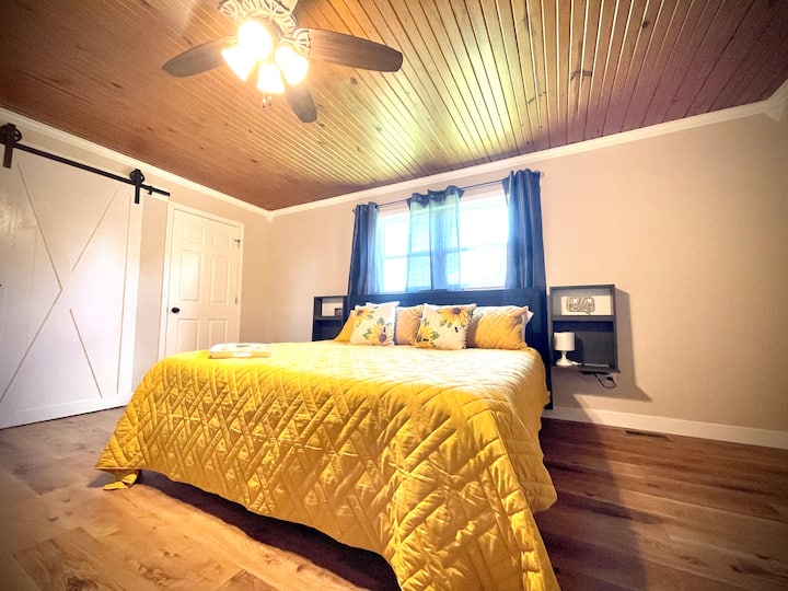 Brand new king size bed with plush pillows, two nightstands and a ceiling fan. The master bedroom also has a walk-in closet a new smart TV a laptop, work area and a bathroom attached.