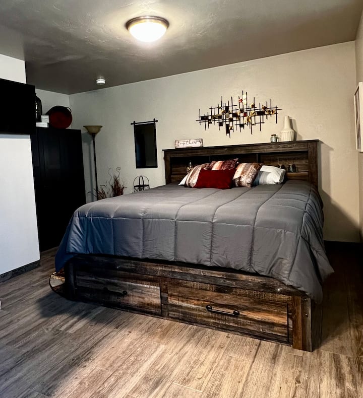 سرير كبير مع تلفزيون مثبت على الحائط 43بوصة في غرفة النوم الرئيسية ؛ تتضمن طاولة السرير الجانبية منفذين لشحن USBC متصلين (الجانب الخلفي العلوي)، باتجاه الجدار. يتم توفير آلة صوت للضوضاء البيضاء (مع مؤقت).