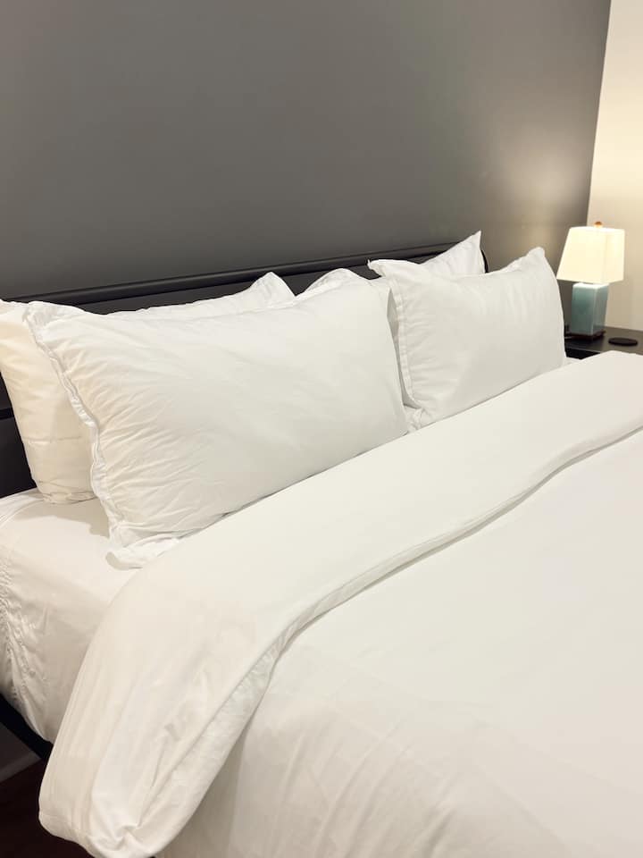 พักผ่อนอย่างสบายใจในห้องนอนที่อบอุ่นนี้ มีเตียงนุ่มพร้อมผ้าปูที่นอนสีขาวสะอาดและหมอนนุ่ม ที่พักที่น่าดึงดูดใจแห่งนี้เหมาะสำหรับการพักผ่อนยามค่ำคืนหลังจากการสำรวจ มอบความสะดวกสบาย การพักผ่อน และความเรียบง่ายที่ทันสมัยสำหรับการเข้าพักของคุณ