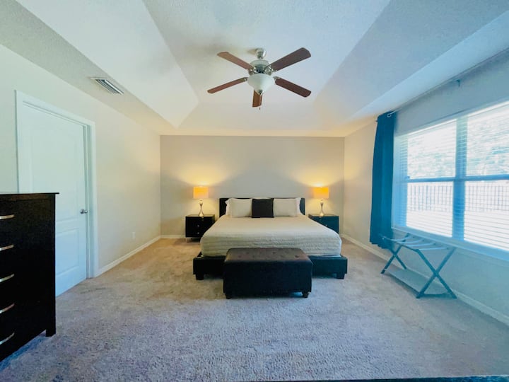 חדר השינה הראשי המרווח כולל חדר רחצה פרטי, עגלת מזוודות, טלוויזיה והדום.