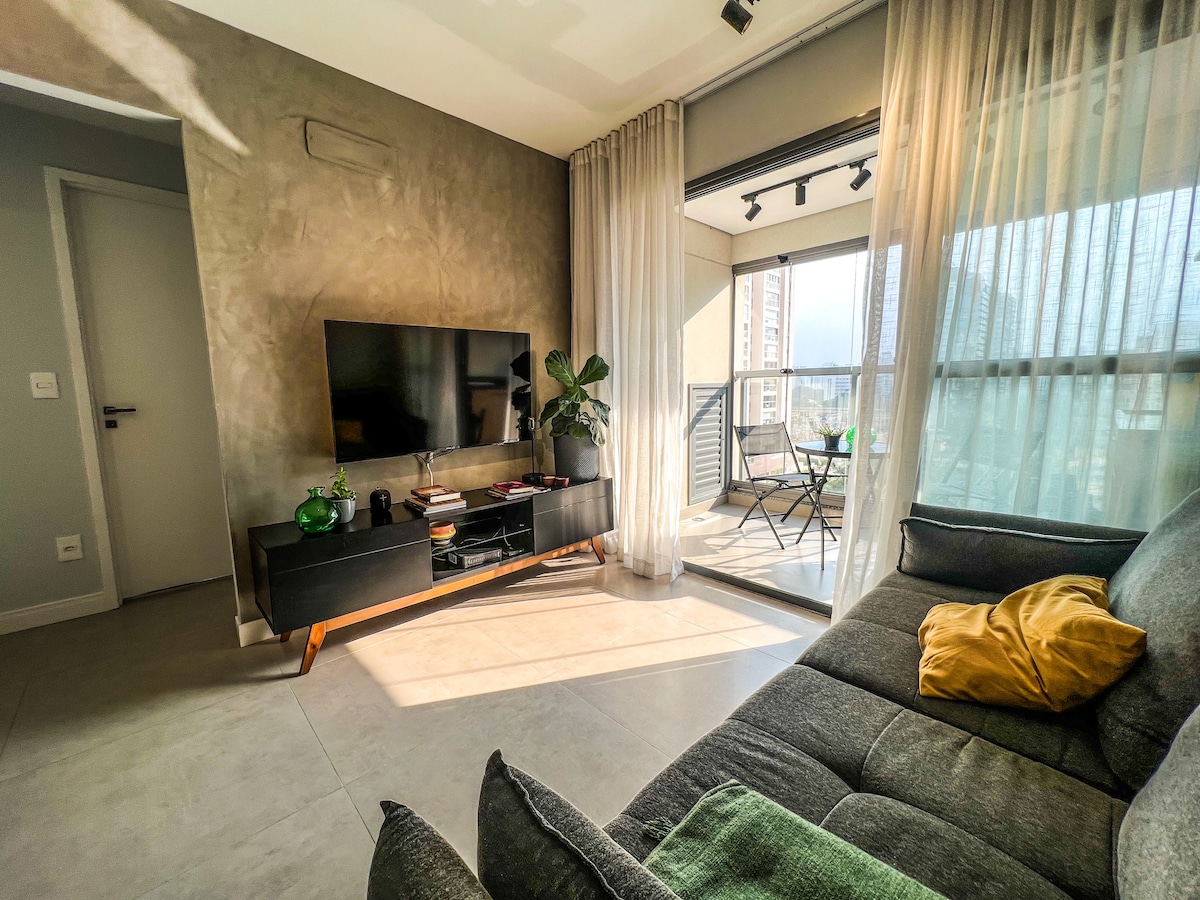 غرفة مشرقة مع سرير أريكة وشرفة مغلقة. 