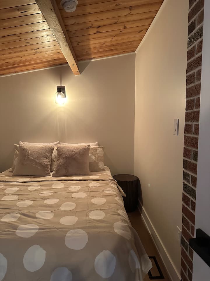 Dormitorio número dos con una cama tamaño queen y mesitas de noche de madera. 