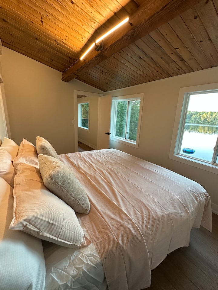 Dormitorio principal con una cama tamaño king con vistas al lago. 