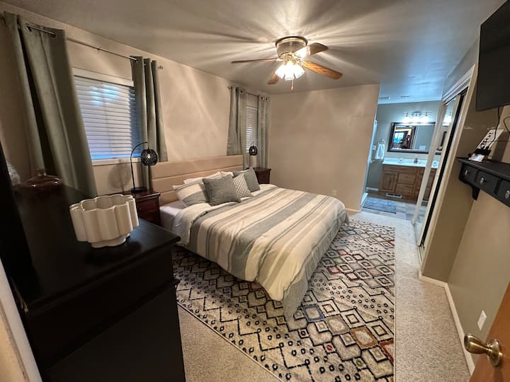 เตียงคิงไซส์ในห้องนอนใหญ่พร้อมห้องน้ำในตัว จุดเด่น: โต๊ะข้างเตียงพร้อมโคมไฟปลั๊กโทรศัพท์ที่เข้าถึงได้ง่ายตู้เสื้อผ้าตู้เสื้อผ้าทีวี 