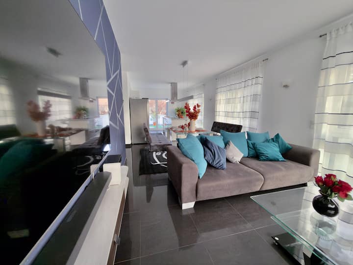 הסלון הפתוח המשקיף למטבח משלב עיצוב מודרני עם חמימות – מושלם לשעות רוגע על הספה או קפה בוקר.