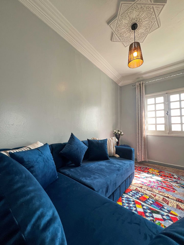 Sebule yenye starehe na angavu yenye sofa nzuri ya bluu, zulia la jadi lenye rangi na maelezo maridadi ya dari. Inafaa kwa ajili ya kupumzika na kufurahia wakati wa utulivu baada ya jasura zako.








