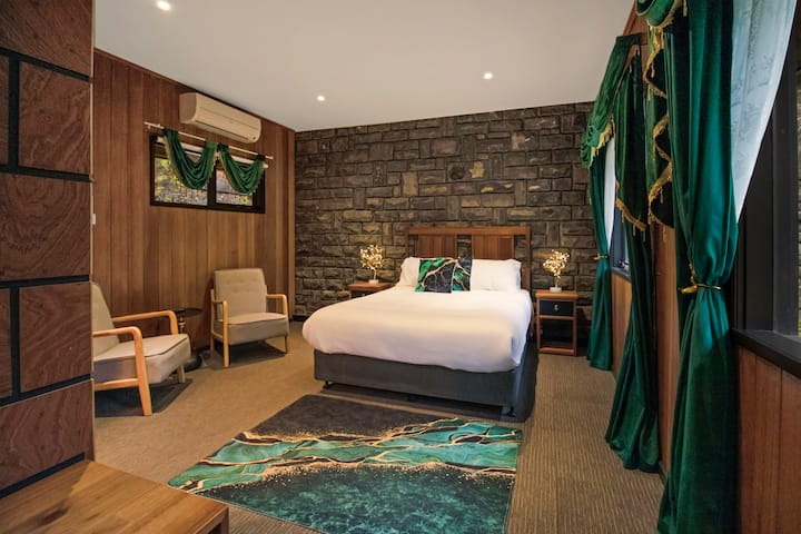 Chambre élégante avec un mur d'accent en pierre, un lit moelleux et d'élégants accents émeraude