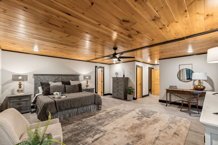 Spacious Master Suite: Relax on plush bedding under a stunning wood-paneled ceiling!