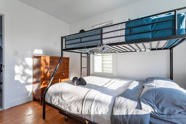 غرفة نوم مشرقة مع سرير كامل بطابقين، وخزانة خشبية، وأشعة الشمس تتدفق عبر النافذة.