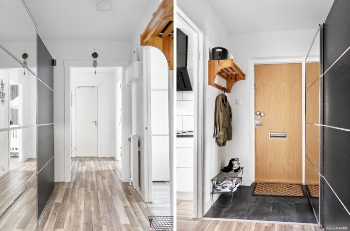 A bright hallway features sleek dark cabinetry on one side, leading to a light-colored door. A welcoming entrance area is displayed with a coat rack and a door mat, while light wood flooring runs throughout the space, enhancing the open feeling of the entryway.