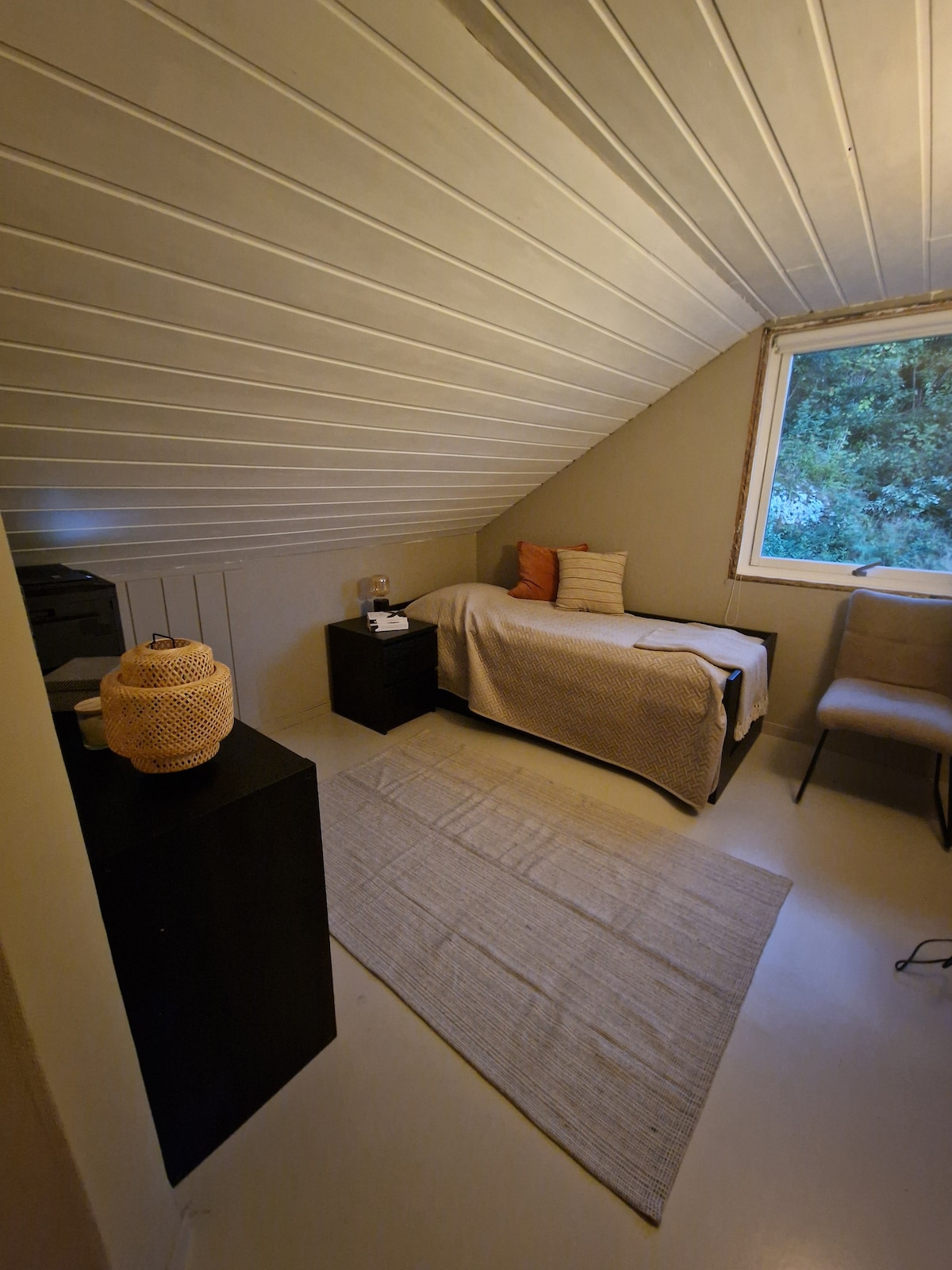 Dormitorio en el tercer piso con una cama que se puede apagar. Vista del área del jardín en la parte trasera de la casa.