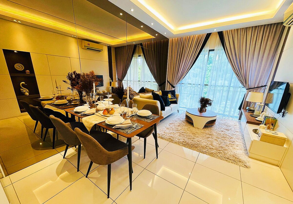 An open living and dining area is showcased, featuring a stylish dining table set for six. The lounge includes a comfortable sofa and a large LED TV, with floor-to-ceiling windows allowing natural light to brighten the space. Soft, neutral tones dominate the decor.