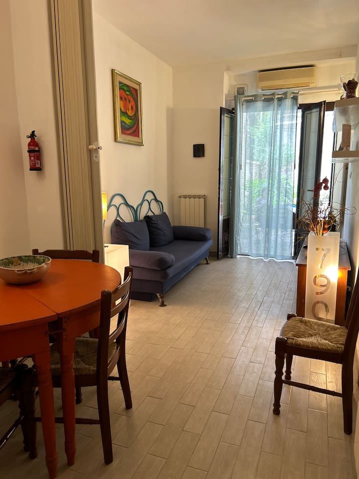 ภาพรวมของห้องนั่งเล่นคลาสสิกในสไตล์อิตาลีที่สมบูรณ์แบบมองเห็นลานบ้านรวมถึงโซฟาที่สะดวกสบายมุมอ่านหนังสือผนังที่มีทีวีจอแบนและโต๊ะขนาดใหญ่ที่ทำจากไม้โบราณที่ทาสีใหม่