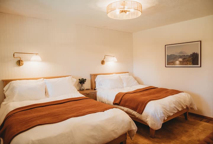 The first downstairs bedroom hold 2 full XL beds, perfect for 4 to sleep comfortably. This room has tall ceilings and an airy feeling, inspired by walking the mountain ridgelines of Olympic National park (photograph on wall is the High Divide Trail).