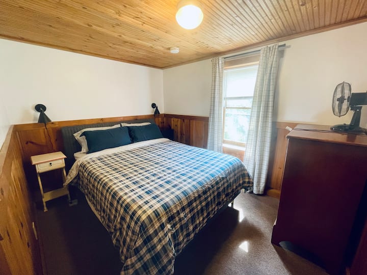 חדר שינה בקומת הקרקע עם מיטת קווין סייז חדשה. 