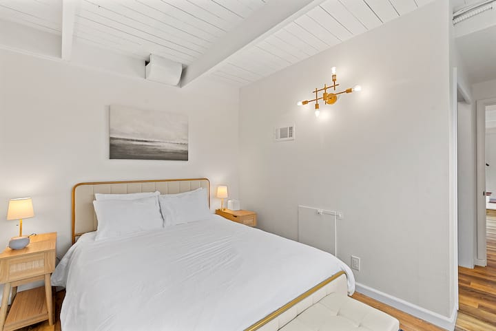 Fourth bedroom with queen bed located downstairs. This bedroom overlooks the spacious backyard, has a full length mirror, sound machine/ alarm clock, and features a low dresser to place suitcases.