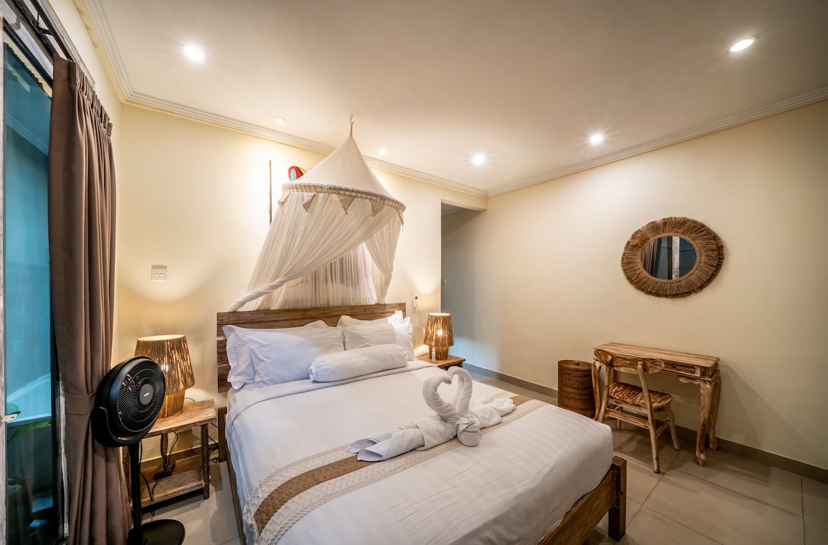 [Salle des bouledogues] Chambre en bas avec lit queen, draps propres, serviettes, bureau et chaise, télévision connectée, placard avec cintres, coffre-fort, miroir, ventilateur, climatisation, rideaux occultants, moustiquaire et espace extérieur. 