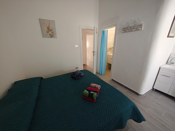 Spálňa s manželskou posteľou a malá toaleta so sprchovacím kútom bez okna 