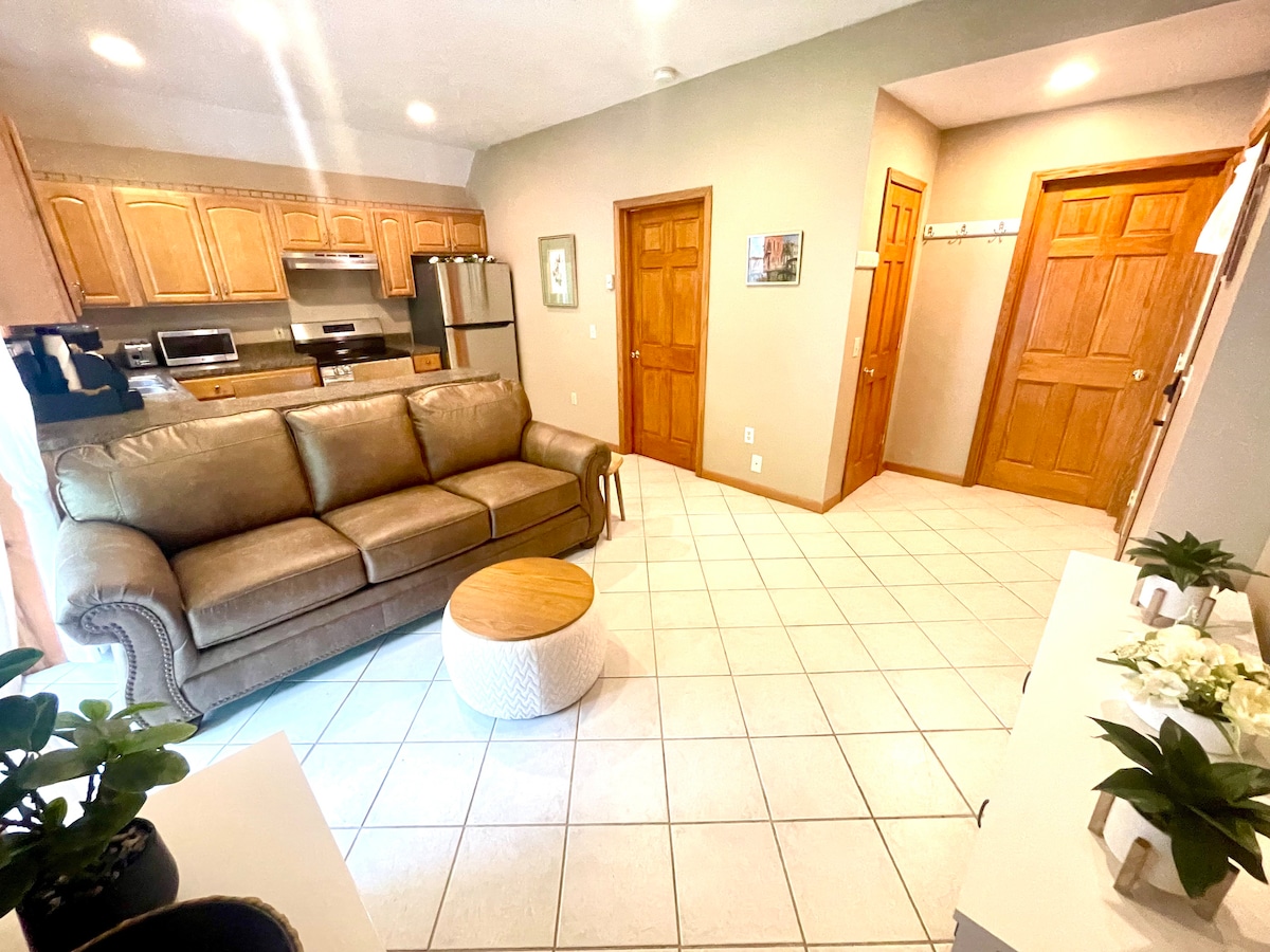 Dhoma e ndenjjes: Hapësirë e ndritshme dhe ftuese me një divan prej pelushi dhe qasje moderne në kuzhinë!