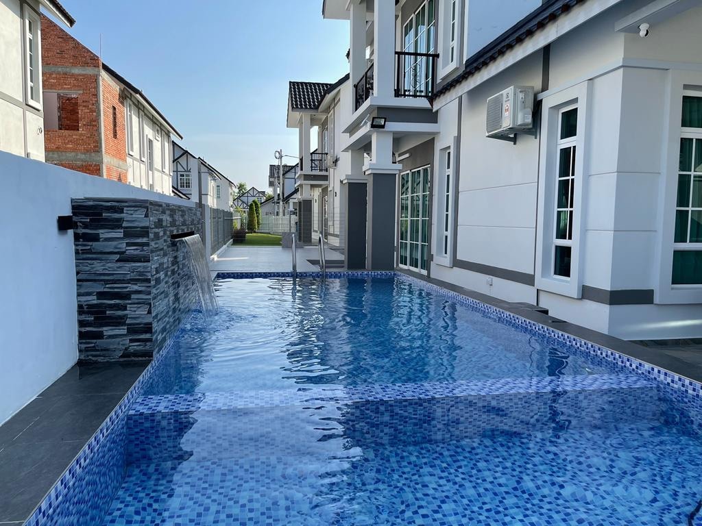 A private swimming pool reflects the clear blue sky, surrounded by modern white buildings. Water features cascade gently into the pool, creating a serene atmosphere. Spacious poolside areas are visible, providing ample room for relaxation.