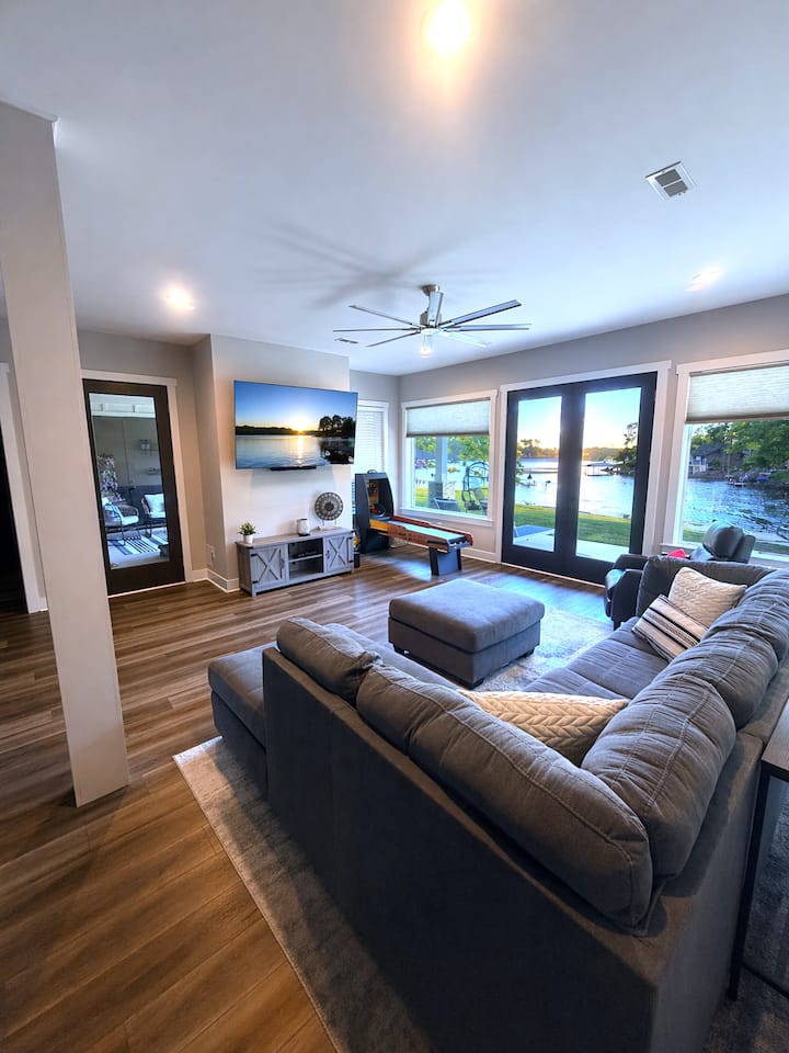 Unwind in this spacious lower-level living area featuring a wall of windows and French doors that open to beautiful lake views.