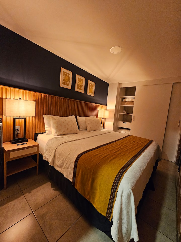 The room combines comfort and style, equipped with a king-size bed dressed in 100% cotton bedding, TV, lamps with USB ports, and a tower fan. It also offers direct access to the open terrace.





