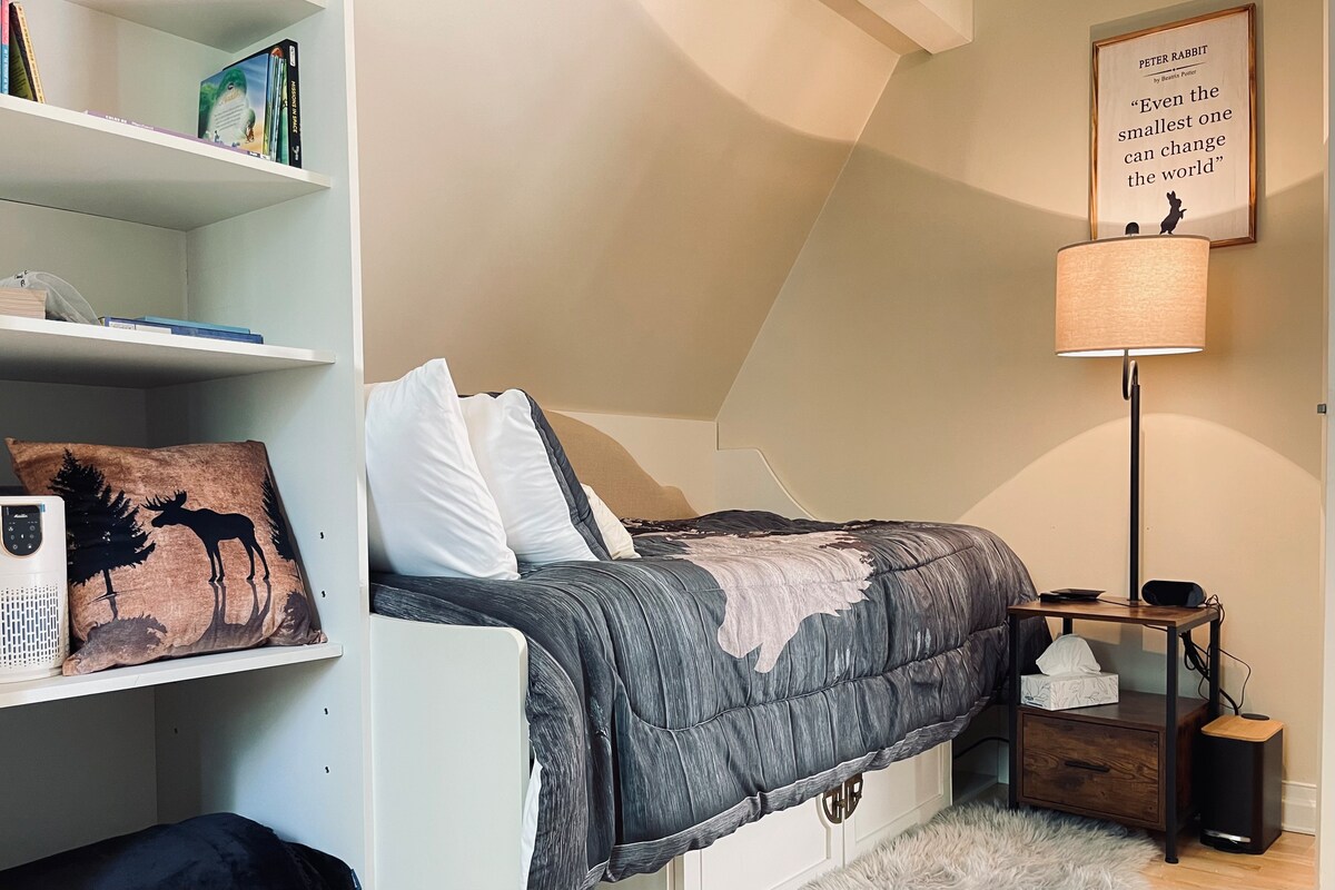 O el tercer dormitorio es perfecto para que un niño se acurruque. Hay un puerto de carga integrado en la mesita de noche. Hay libros infantiles en la estantería. 