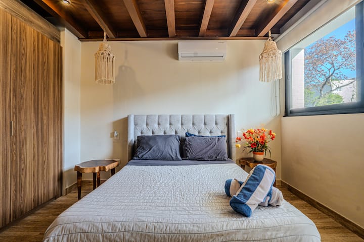 Detalles en madera cálida y ropa de cama lujosa para una estadía acogedora y relajante en Playa del Carmen.