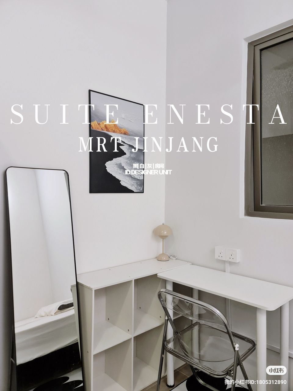 A compact workspace is visible, featuring a white desk paired with a clear acrylic chair. A piece of wall art depicting abstract scenery adds interest above the desk. Natural light enters through a large window, enhancing the bright and airy feel of the space.