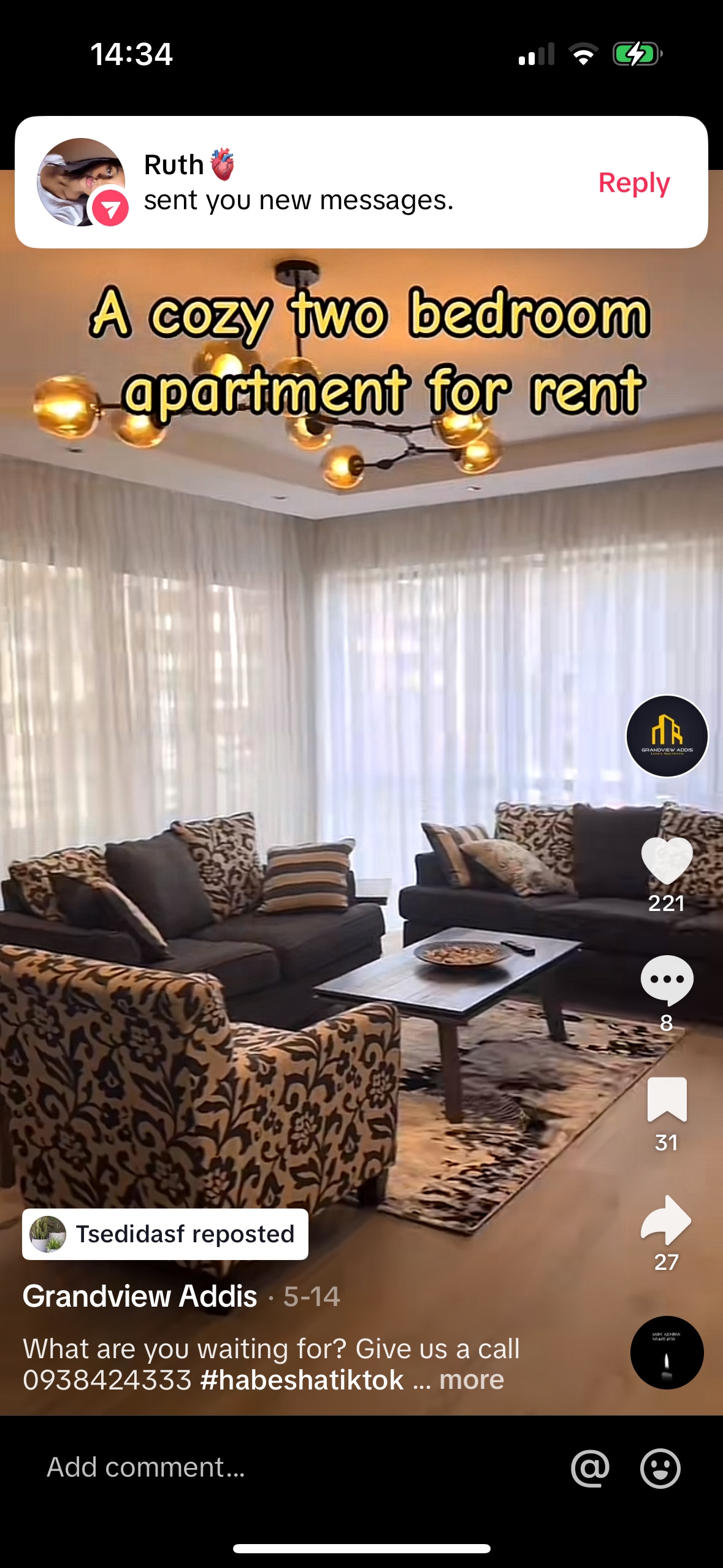 A living area is presented with comfortable seating arranged around a central coffee table. Soft natural light filters through sheer curtains, enhancing the inviting ambiance. A patterned rug grounds the space, while light fixtures adorn the ceiling, contributing to the overall design.