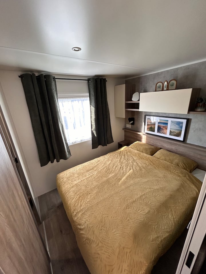 濃い緑色の暗いカーテンの寝室。 
電話を充電するためのベッド接続の横。 