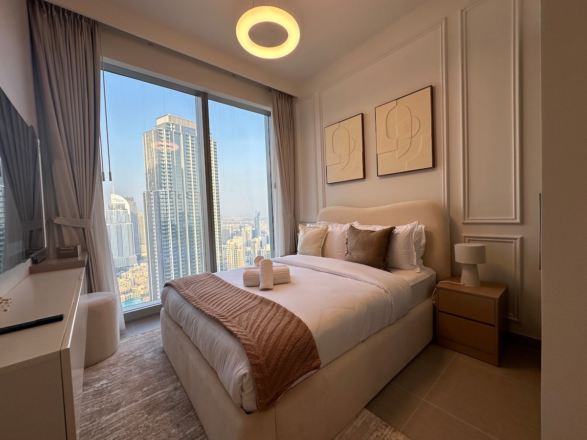 בחדר השינה יש חלונות גדולים עם נוף מדהים לעיר. הוא כולל מיטה נוחה עם מצעים לבנים וזריקה בצבע בז', כריות נוי, שידות לילה עם מנורות ואמנות מופשטת על הקירות, ויוצרת אווירה מודרנית ושלווה.