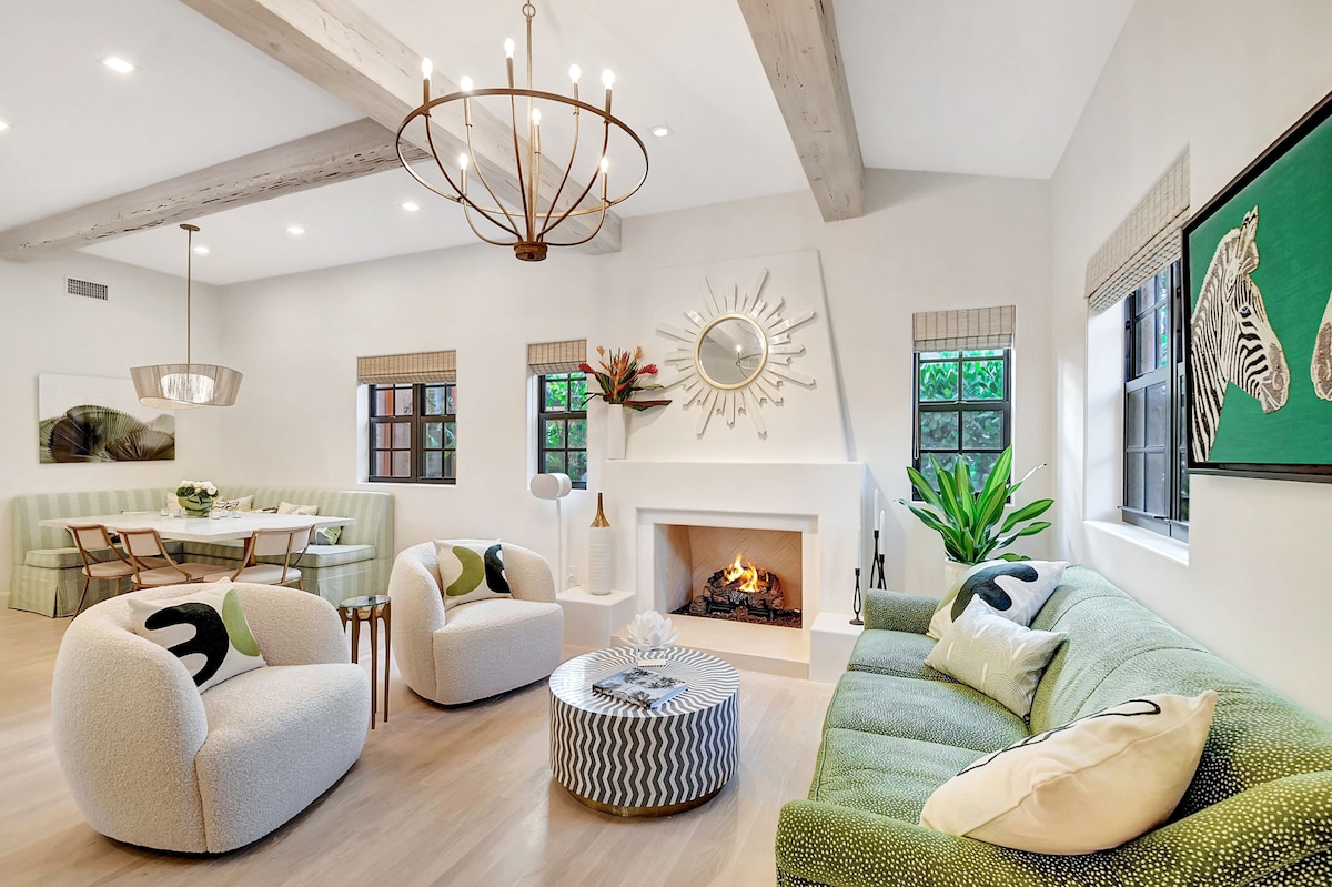 Living room with gas fireplace, exposed beam ceilings, and open flow to the dining banquette — a warm, comfortable gathering space for the whole group.