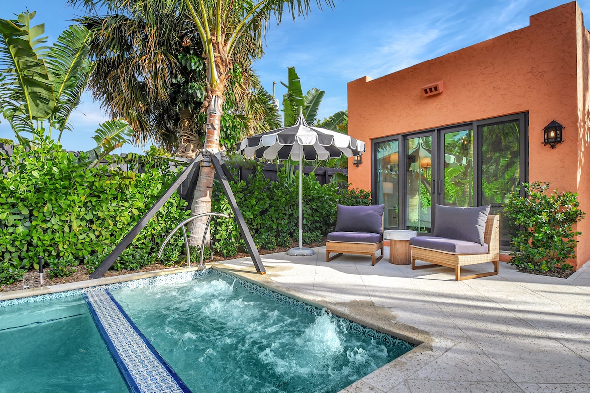 The spa terrace anchors the pool deck, with wicker lounge seating and a black-and-white market umbrella completing the scene.