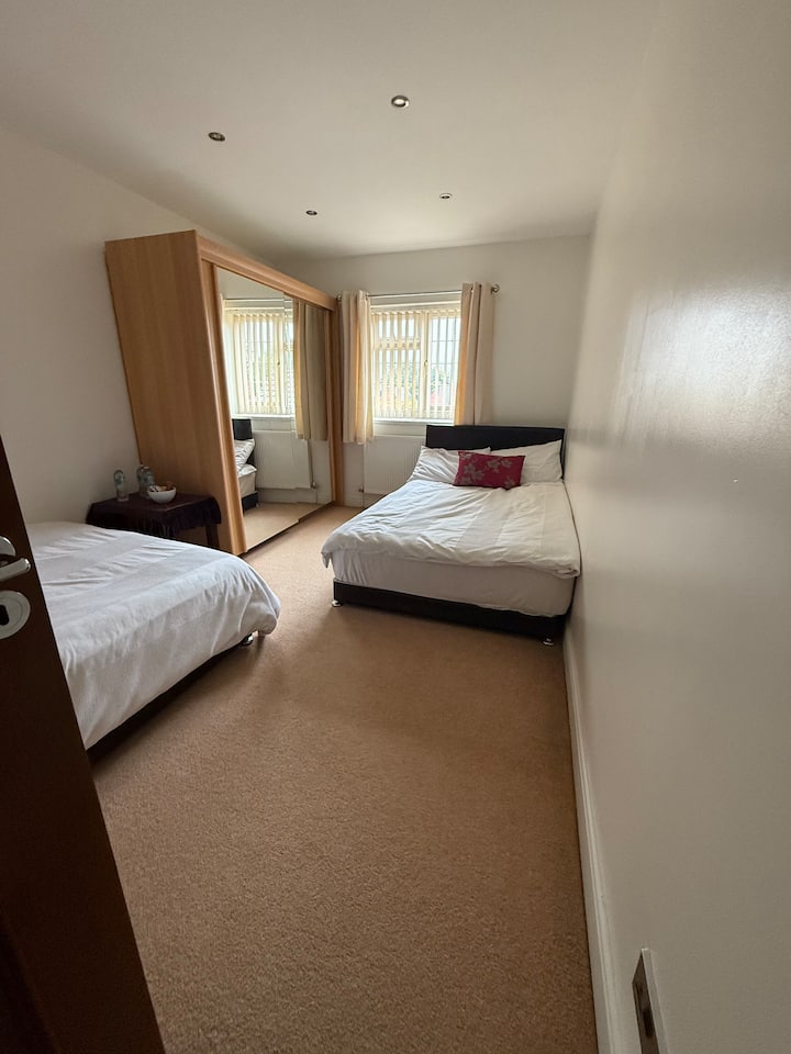 View of the bedroom from the door, showing 2 double beds; one behind the door and one on opposite wall under the window.