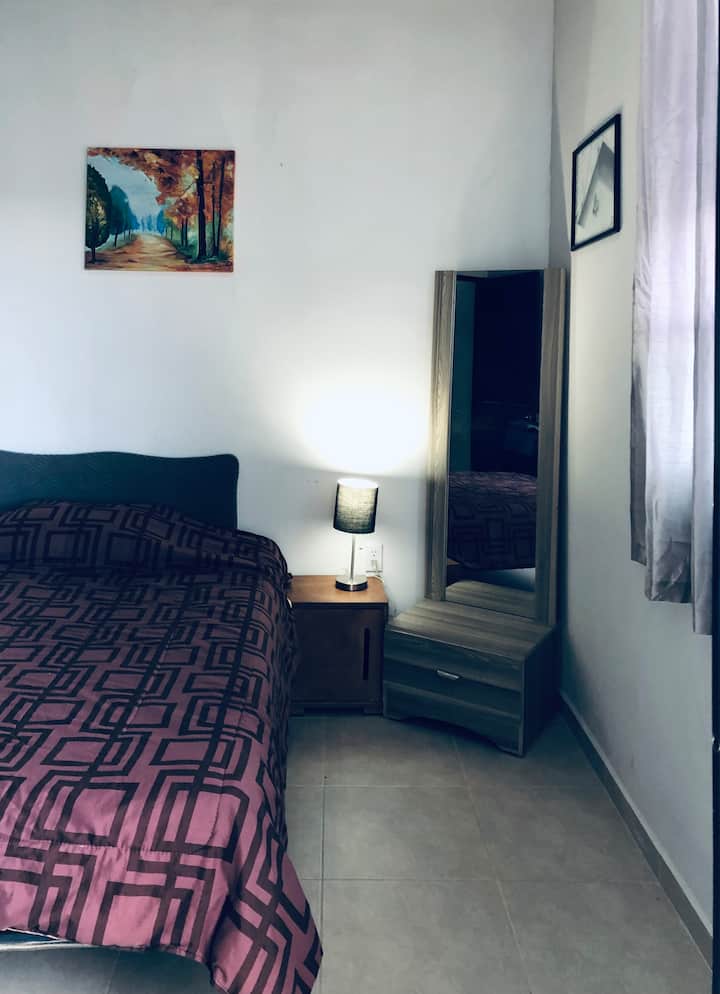 Cómoda recámara secundaria con cama matrimonial, cobija adicional y acceso a un balcón compartido, perfecta para un descanso tranquilo y cómodo