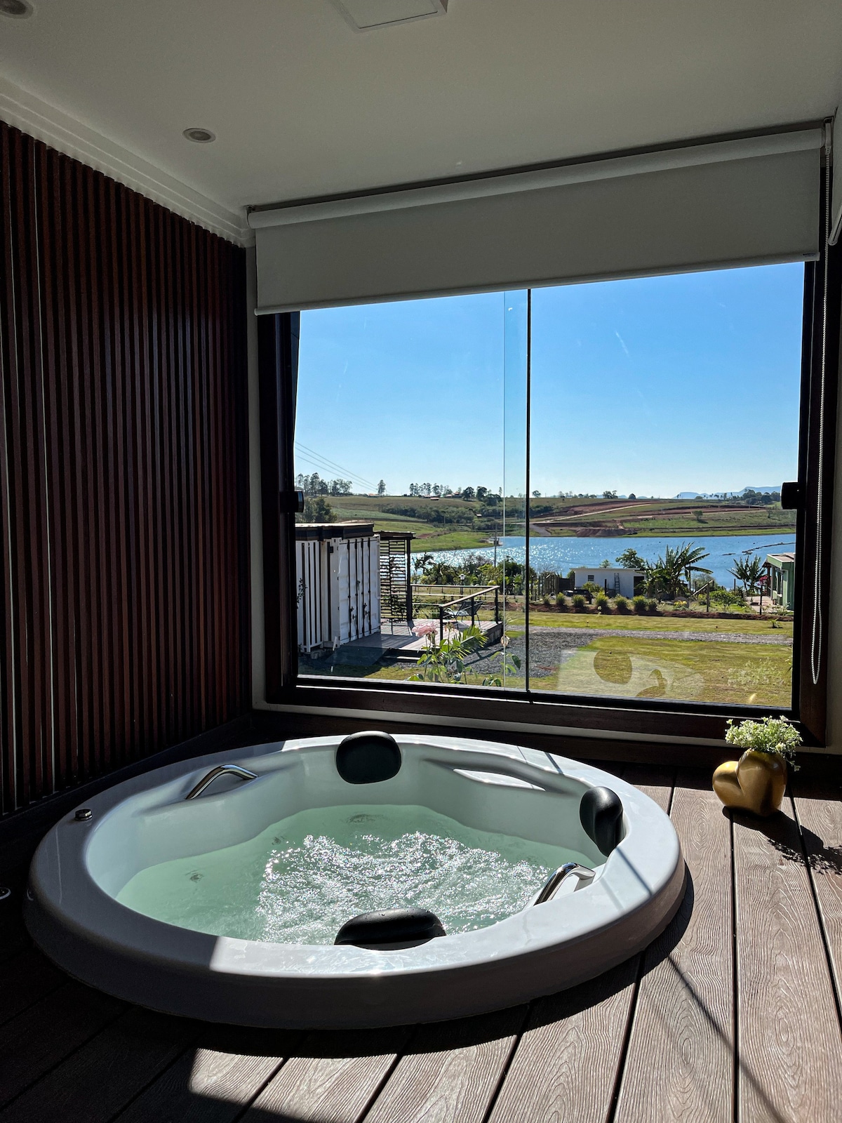 A spacious hot tub sits against a large window, revealing picturesque views of the surrounding landscape. Natural light floods the room, highlighting the sleek design and inviting atmosphere of the space, where relaxation is emphasized.