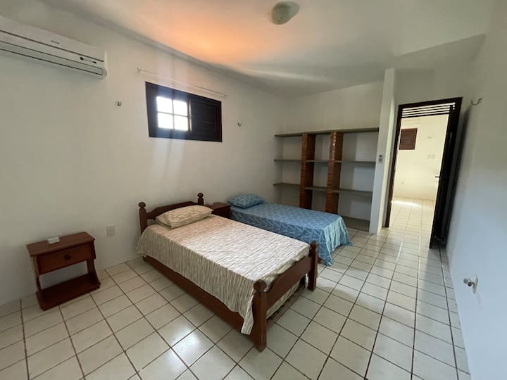 Large bedroom with windows on two sides, en suite bathroom and three single beds.